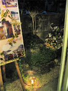 居間から庭に置いたメモリアルボード、通夜　庭で夕闇の中にともるキャンドルの明かり